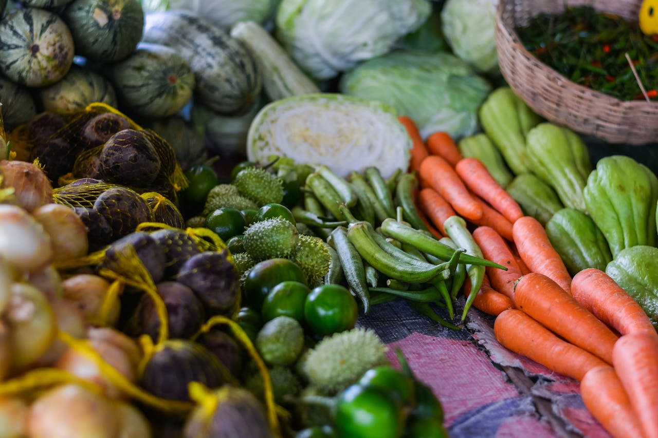An array of fresh vegetables displayed at an outdoor market stall, showcasing a variety of produce.